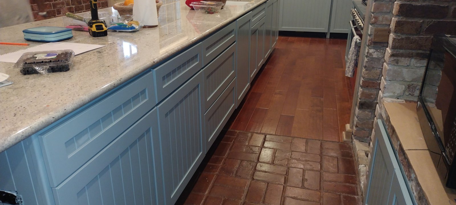 Refinished cabinetry paired with a red range and brick flooring