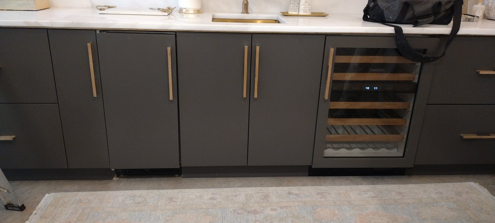 Dark refinished cabinetry with waterfall island and built-in wine fridge
