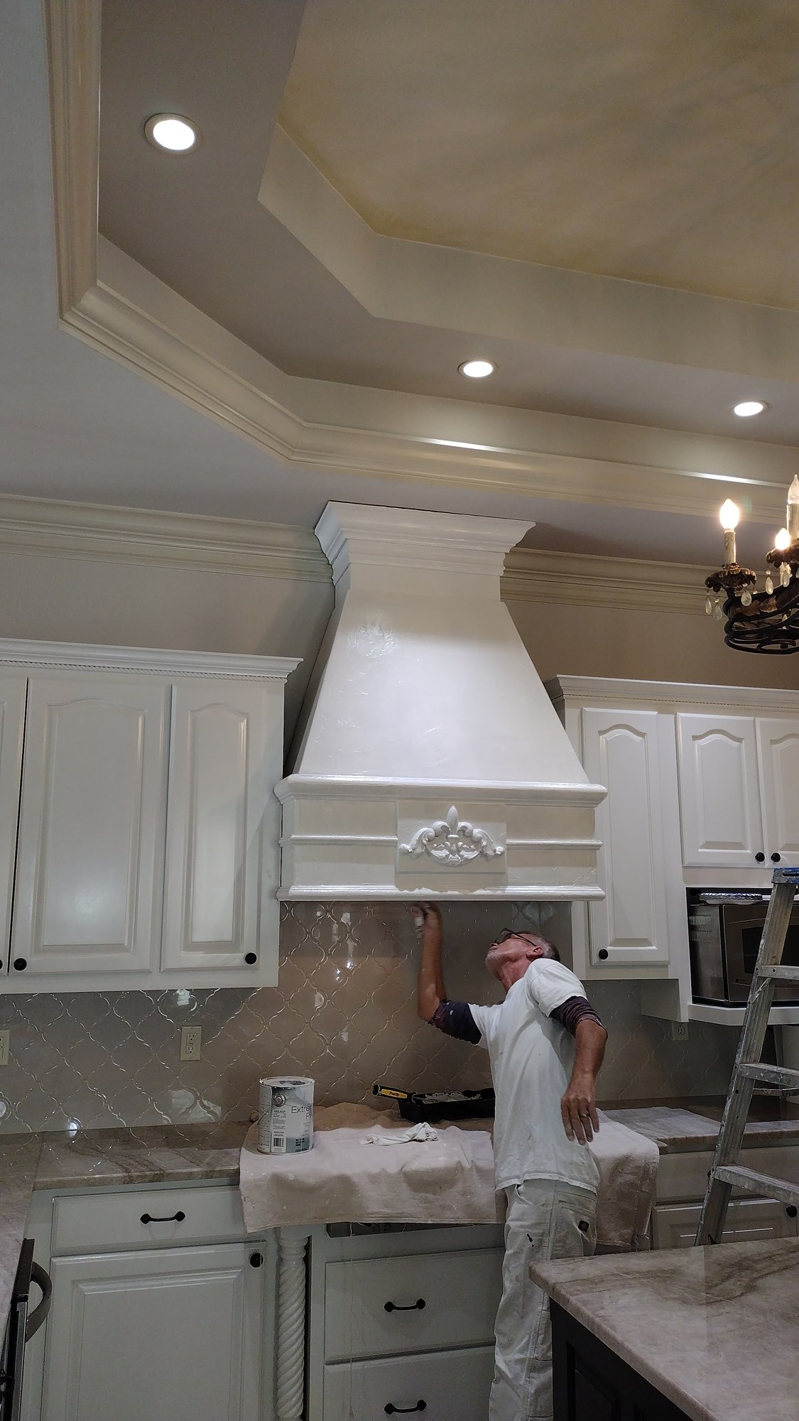 Howard's Painting crew member applying paint to a cabinet range hood