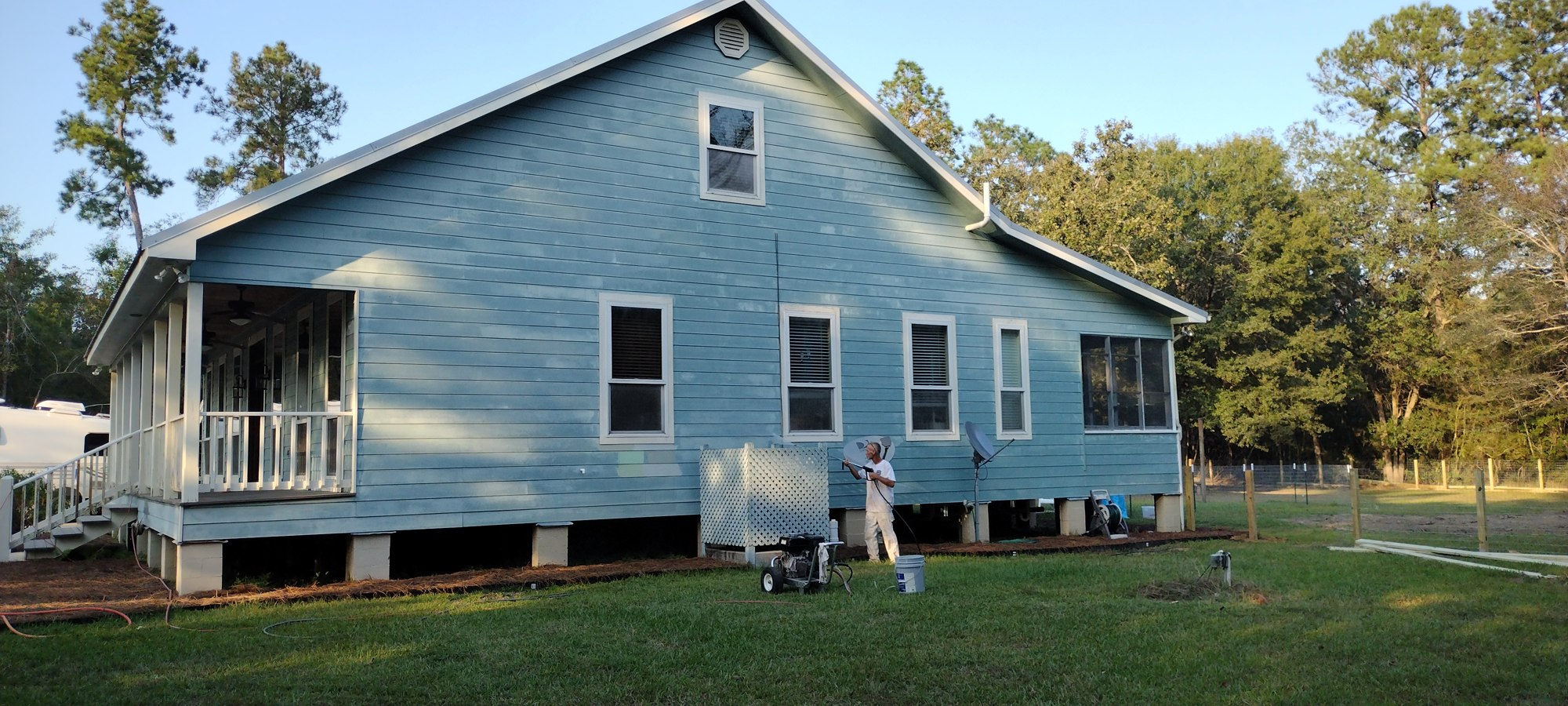 Painter on a ladder repainting exterior siding
